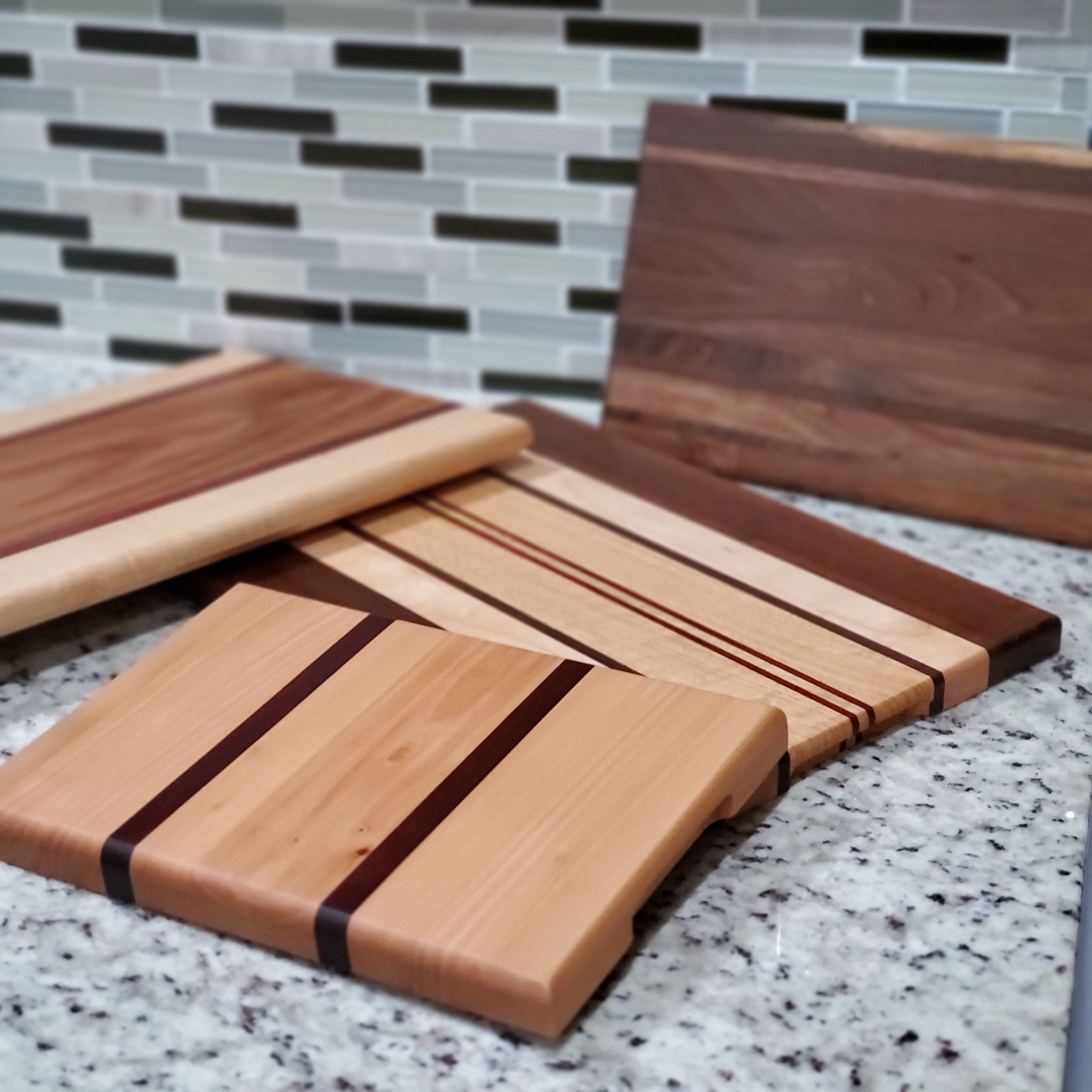 Set of wooden cutting boards on a kitchen counter with a tiled backsplash.